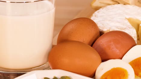 a selection of eggs, nuts, milk, cheese, and seafood displayed on a wooden table.