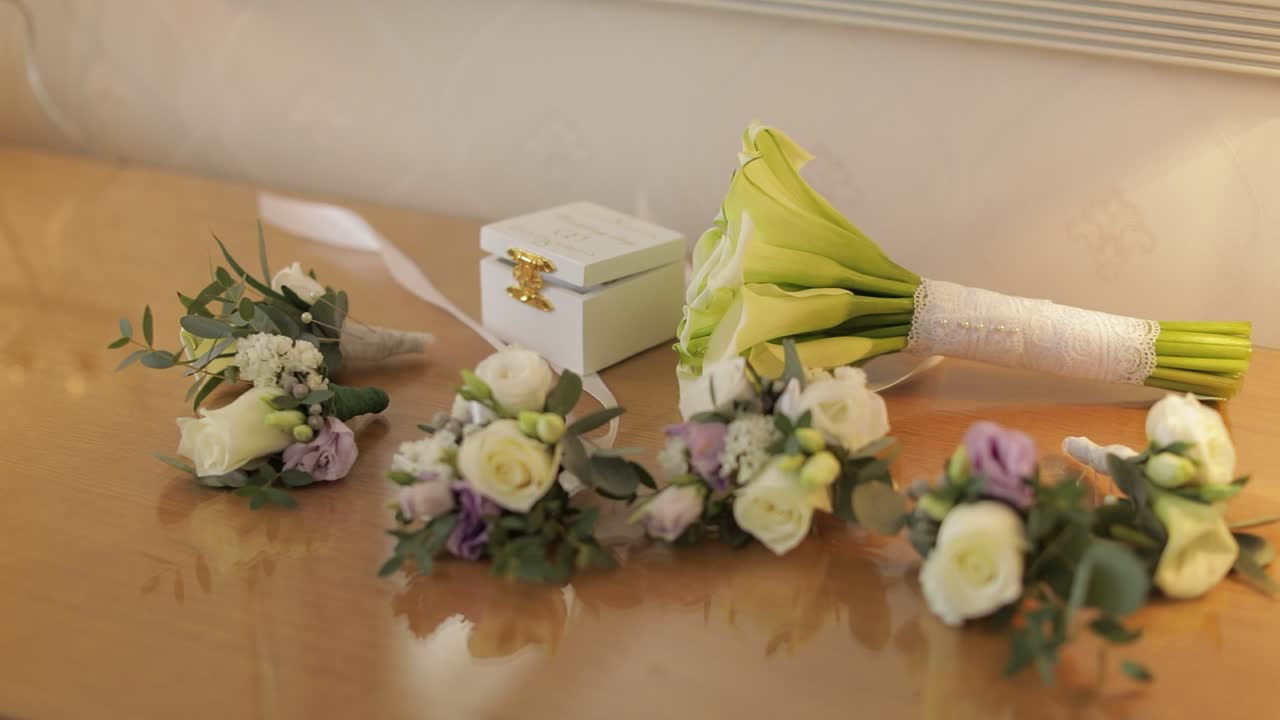 Beautiful wedding bouquets lie on a table near box with wedding rings