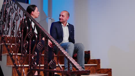 Businesspeople-taking-a-break-sitting-on-stairs-talking