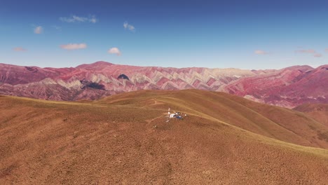 aerial rising shot revealing the cerro de los 14 colores from behind a mountain