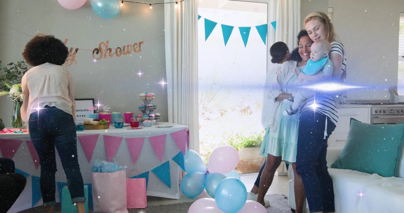 Organizador de eventos levantándose, organizando tazas para un baby shower mientras la homenajeada saluda a una amiga que sostiene un bebé.