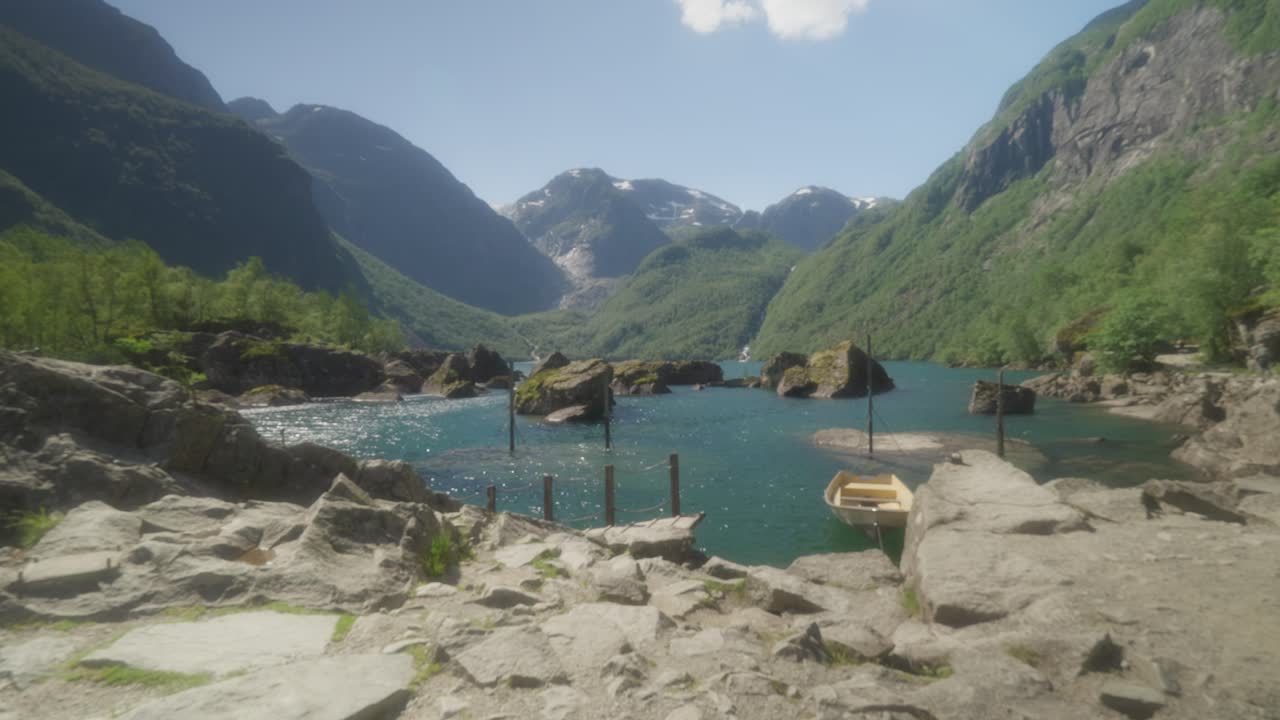 People hiking on a rocky path by a beautiful turquoise lake surrounded by mountains