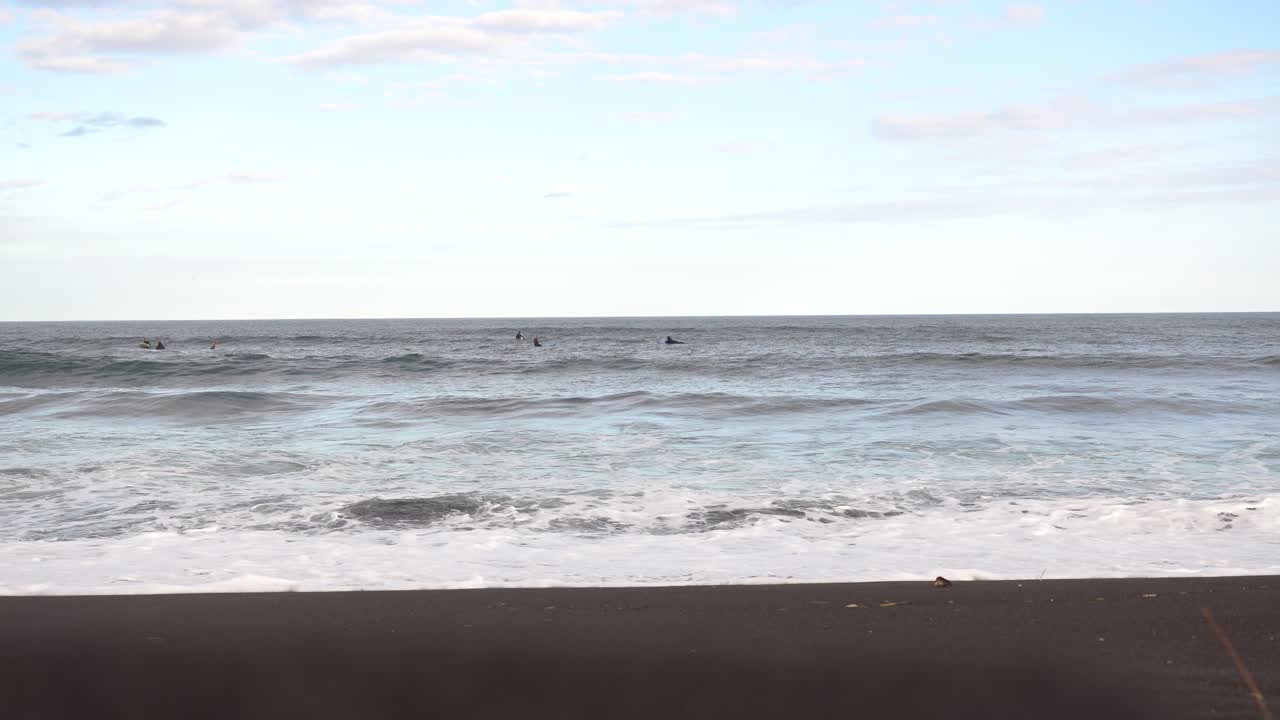 Surfers on a Black Sand Beach