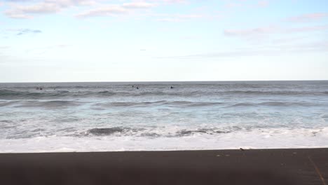 Surfers on a Black Sand Beach