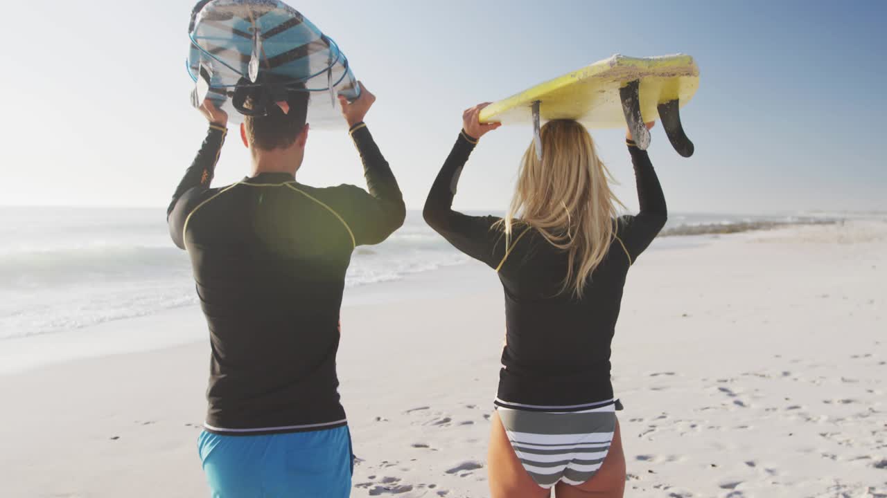 Couple walking onto beach carrying surfboards as animated social media prompts appearing and fading