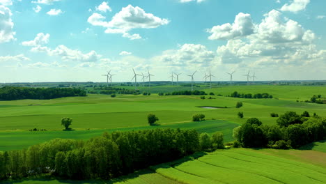 Wind-turbines-on-a-sunny-day,-standing-tall-in-a-vast-green-field-with-blue-skies-and-scattered-clouds