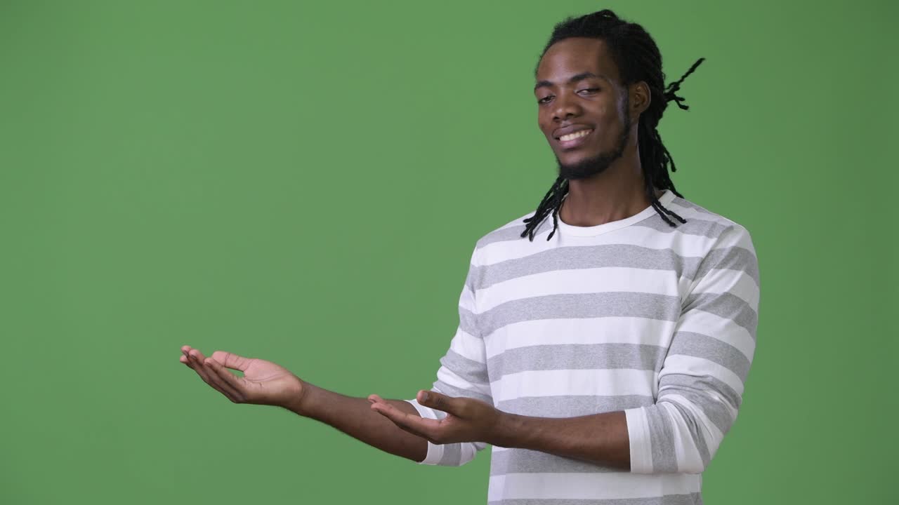 Young handsome African man with dreadlocks against green background