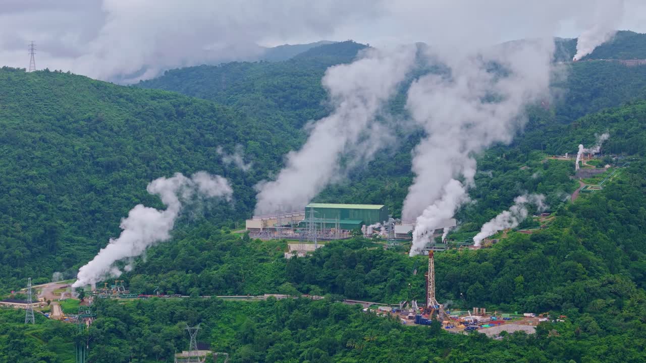 Steam rises from multiple geothermal plants in lush volcanic mountains above Ormoc, Philippines.
