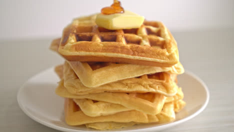 pouring honey or maple syrup on stack of waffles