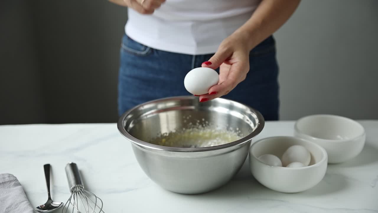 Vrouw bakt: eieren toevoegen aan beslag