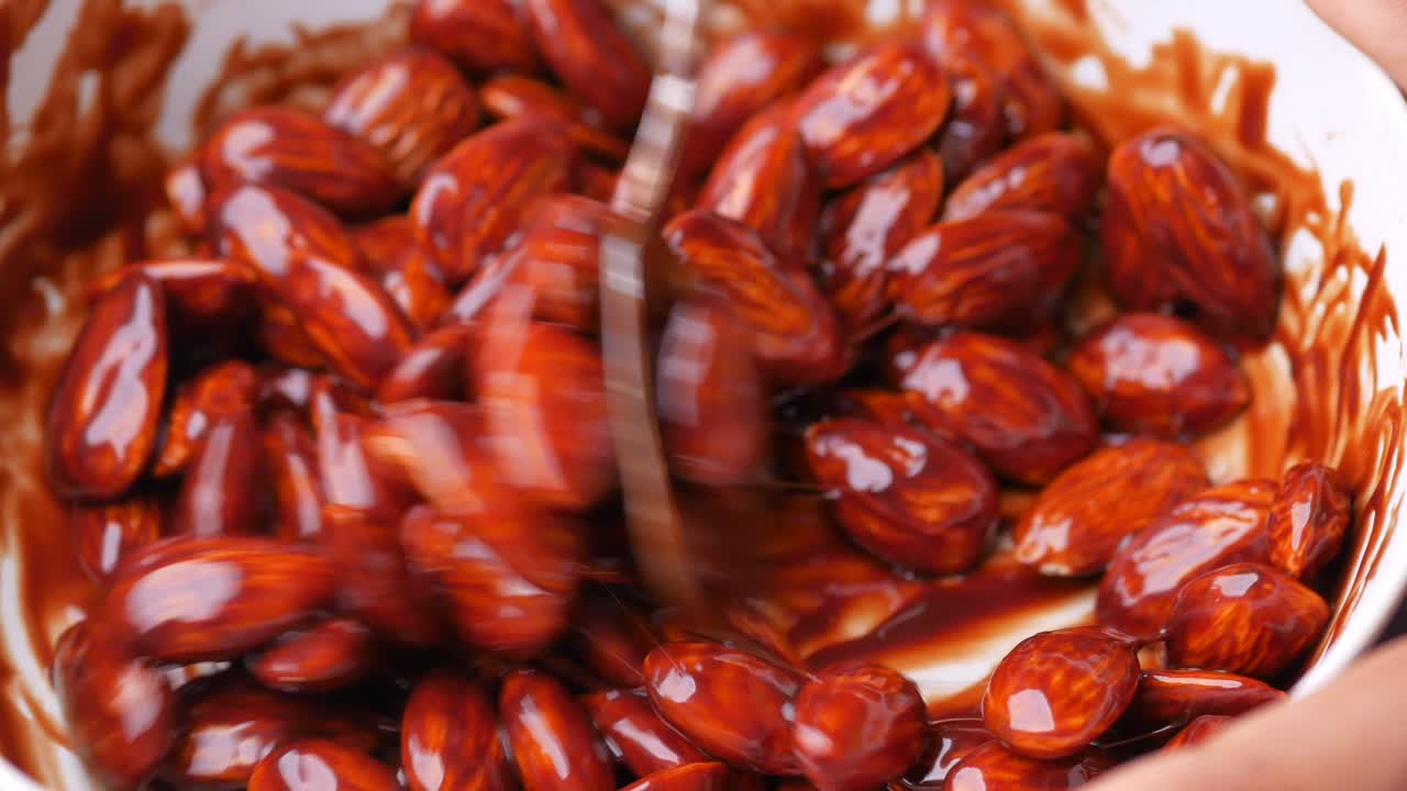 Crema de chocolate oscuro vertida sobre nuez de almendras en blanco