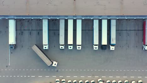 aerial view of a semi trucks with cargo trailers standing on warehouses ramps for loading unloading goods on the big logistics park with loading hub