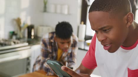 video of happy african american male teenage friends using smartphones, slow motion