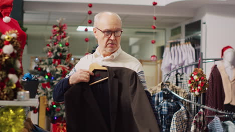 Hombre-Mayor-Examinando-Elegantes-Blazers-En-Una-Bulliciosa-Tienda-De-Compras-Durante-La-Temporada-De-Vacaciones-De-Invierno.-Cliente-Anciano-En-Una-Tienda-Decorada-Navideña-Comprobando-El-Tamaño-De-La-Ropa,-Buscando-Un-Ajuste-Perfecto