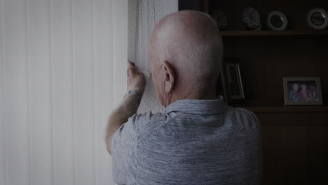 elderly man adjusting window blinds