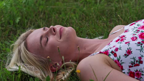 Close-up-shot-of-young-pretty-girl-with-dress-lying-on-grass-in-nature-during-summer-day
