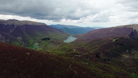 forested mountains with old radar dome on summit under cloudy sky, aerial view