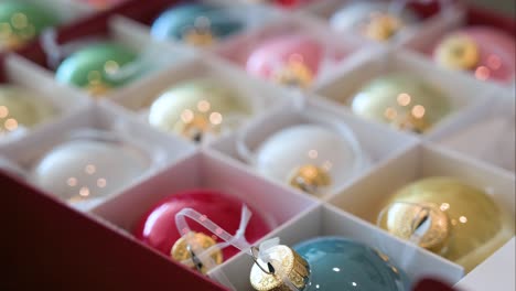 se ven bolas de árboles de navidad de colores con un acabado brillante empaquetadas en una caja