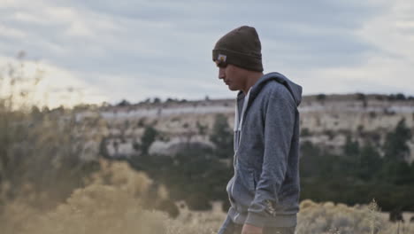 young man walking through desert with sunset sun behind him, slow motion