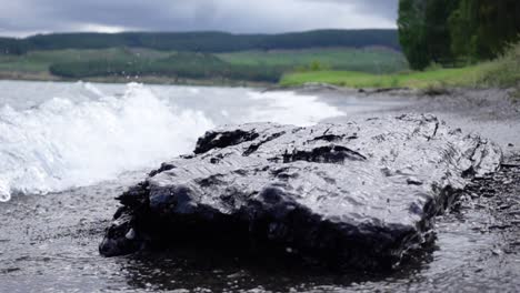 浪潮在 taupo 湖岸上的大黑岩石上散射,慢动作