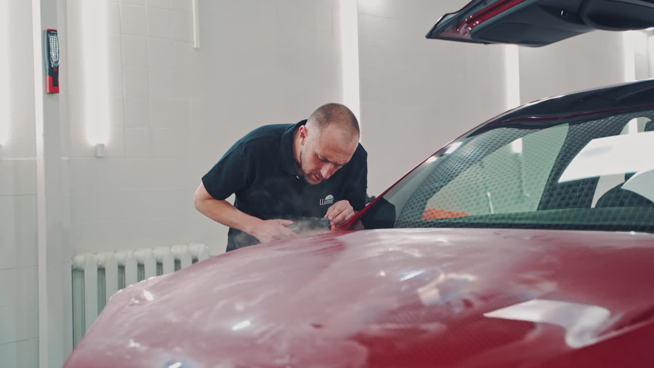 Special work with car. Close up of installation process foil on hood