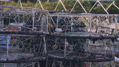 a close-up of crab fishing cages piled up at the fishing dock ready for use during the crabbing harvesting season lobster seafood industry plastic blue bins in background