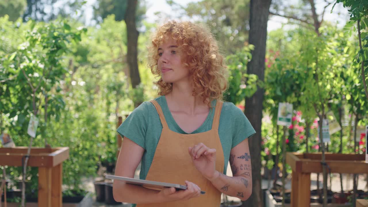 mujer usando tableta en vivero de plantas
