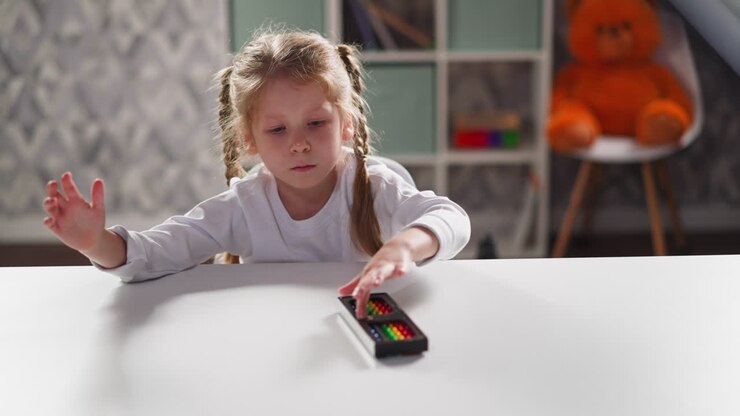 Little child plays with abacus sitting at desk at maths