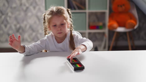 little child plays with abacus sitting at desk at maths