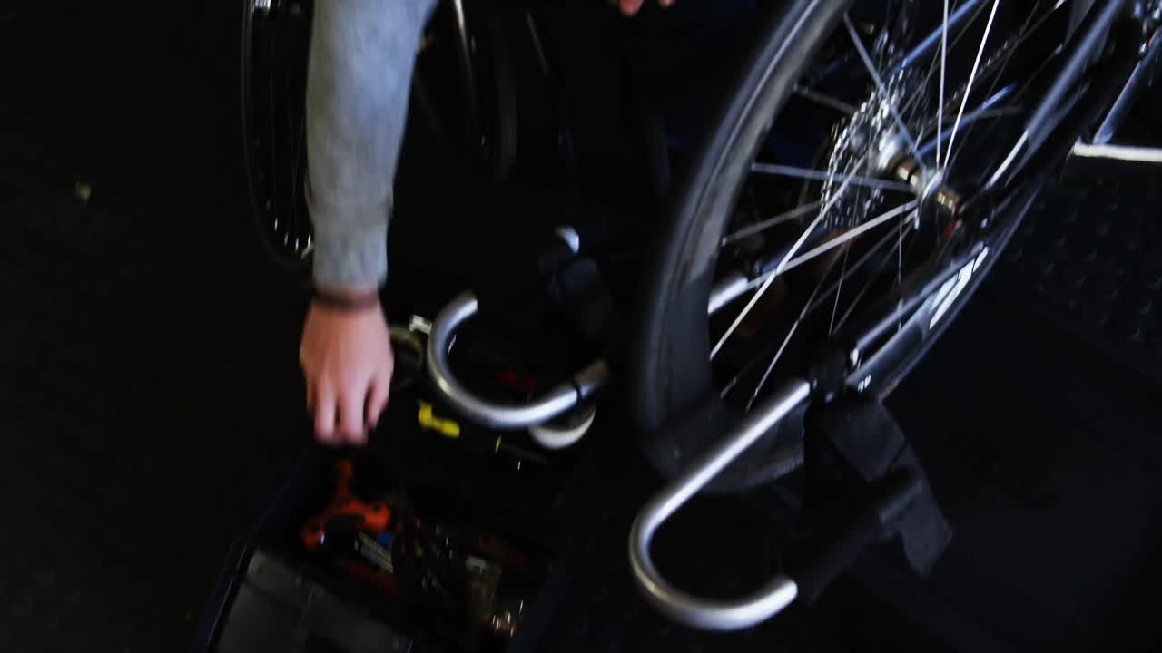 hombre discapacitado reparando una silla de ruedas en el taller 4k