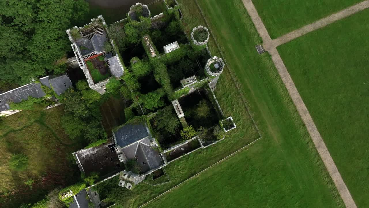 Castle Saunderson, County Cavan, Ireland, September 2022. Drone in Bird's Eye View rotates above the ruined Castle featuring towers stairs and overgrown interior filled with wild Ivy greenery.