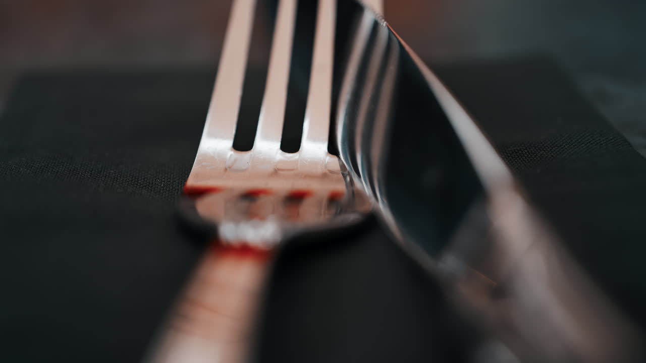 Close up of silver cutlery placed neatly on a dark napkin at a restaurant