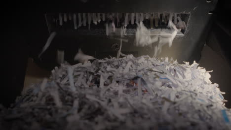 Shredder-Cutting-Paper-From-Below,-Very-Full-Basket,-Hard-Light