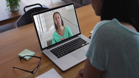 mujer afroamericana haciendo una videollamada con una colega de oficina en una computadora portátil en casa
