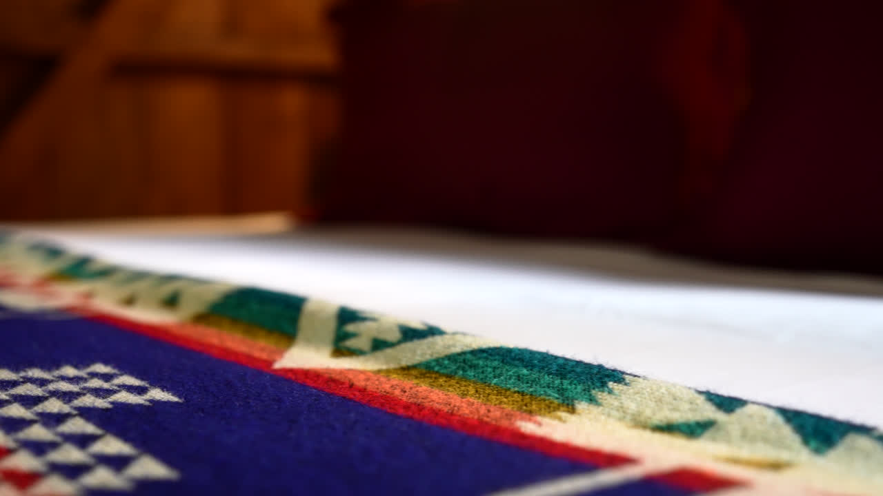 Close-up of bedding details inside an eco-lodge in Mindo, Ecuador with intricate traditional woven textile fabrics with Central America stylized patterns