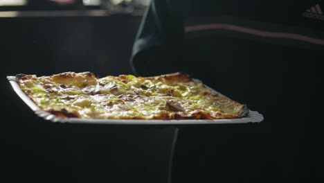 close up shot of a german flat bread pizza with mozzarella cheese tomatoes and bread salad stone oven fresh baked serving it to the guests 50 fps slowmotion