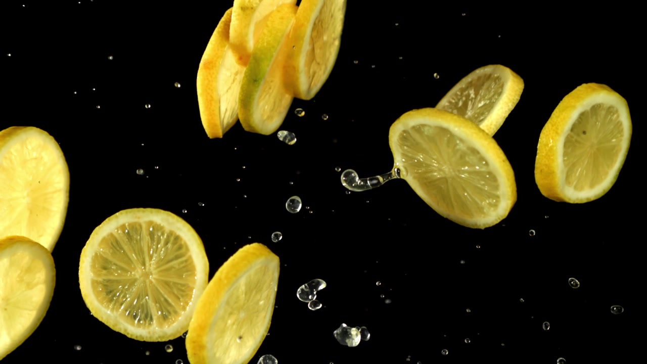 Fette di limone fresco che cadono e schizzano acqua al rallentatore