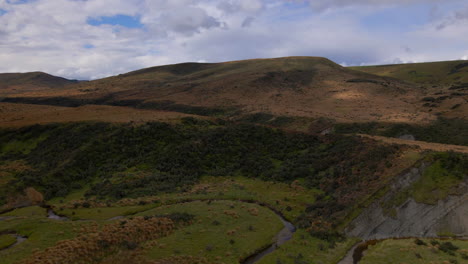 Small-wild-stream-with-curves-in-wild-hill-brown-landscape-in-New-Zealand