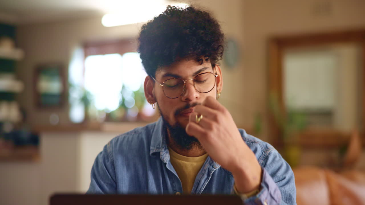 A man in a blue shirt sits at his desk, concentrating on his work.