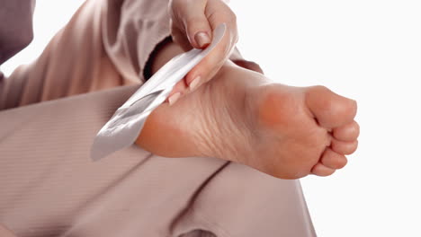 hands peeling off the backing of a large white adhesive bandage, preparing for application