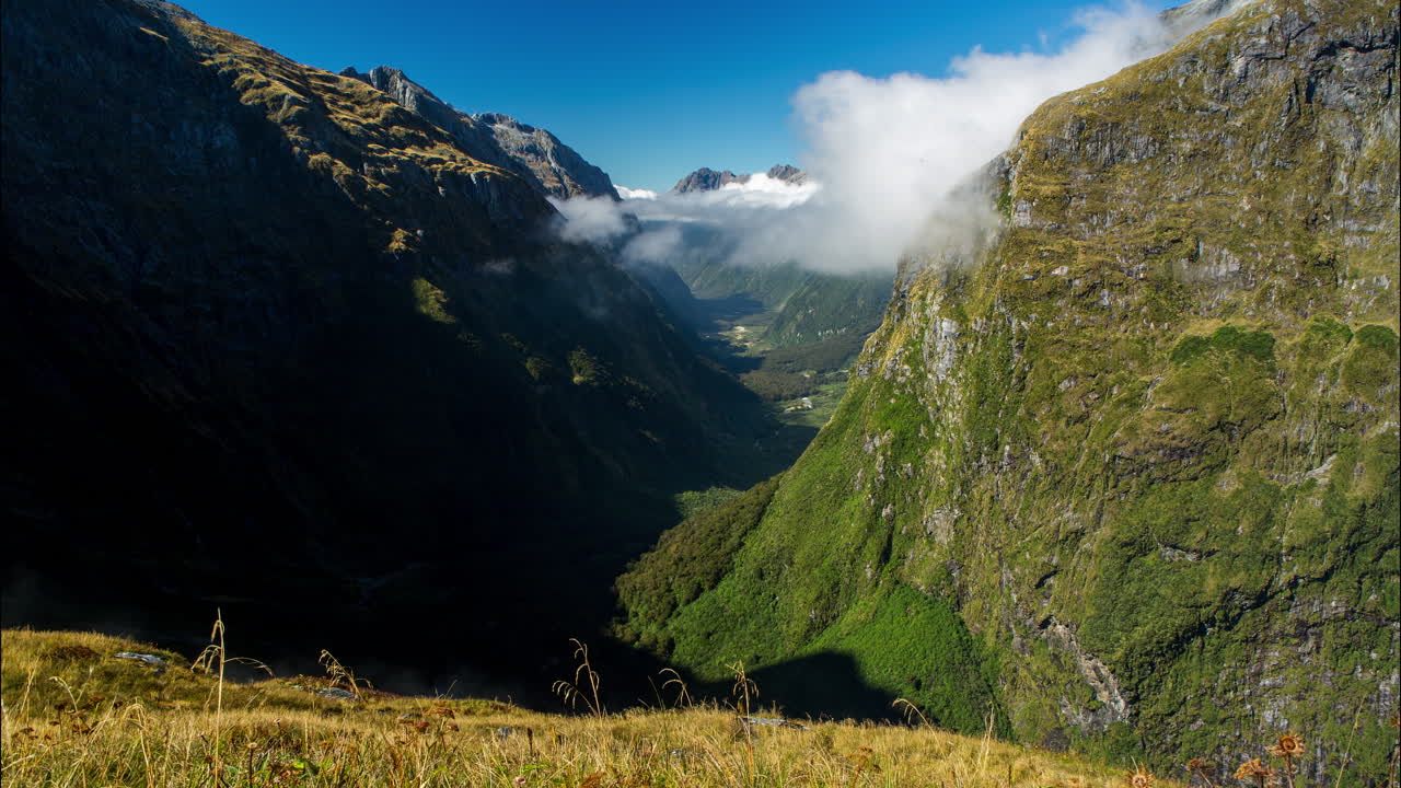 Time lapse of low clouds moving through a deep beautiful valley in Fjiordland National Park, New Zealand