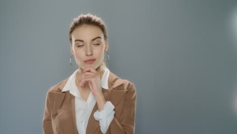 thoughtful business woman looking at product on gray background