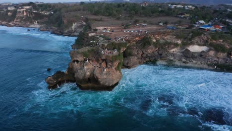 orbit twilight aerial around rocky cliff over indian ocean on bali island indonesia