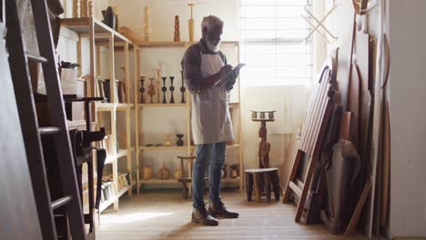 African-american-male-carpenter-writing-on-clipboard-in-a-carpentry-shop