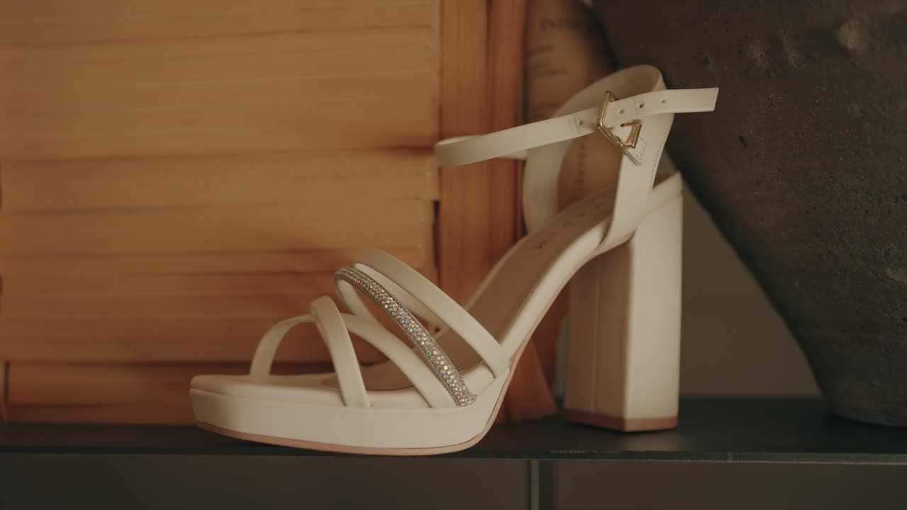 Chic white block heel sandal featuring multiple straps and rhinestone detailing displayed indoors