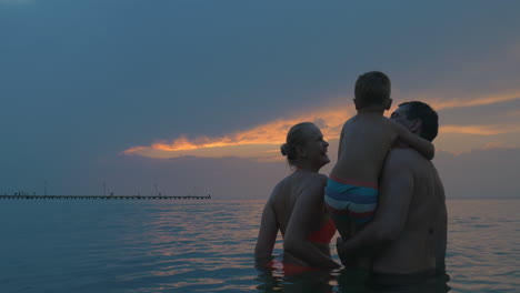 parents and son enjoying evening sky while bathing