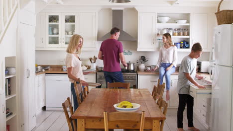 family with teenage children preparing breakfast in kitchen