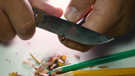 Footage-of-hands-slowly-sharpening-a-pencil-and-some-coloured-pencils-with-a-sharp-knife