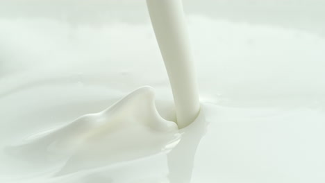 pouring creamy lotion into white milky liquid making a splash and in macro and slow motion