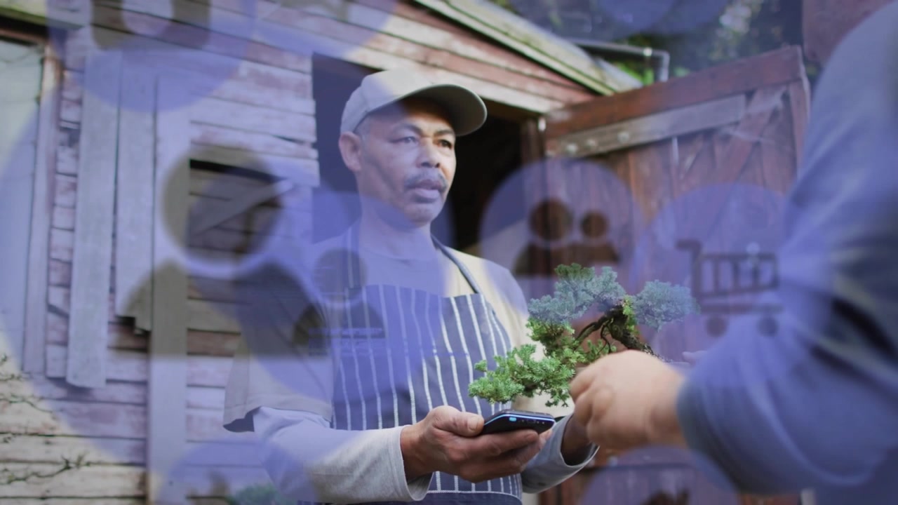 Nursery Worker Using Smartphone to Manage Bonsai Tree Sale